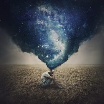 State of mind and mental health concept as a melancholic lone person seated in an open land suffers burnout. Dark smog comes out of man head and transforms into a galaxy of thoughts