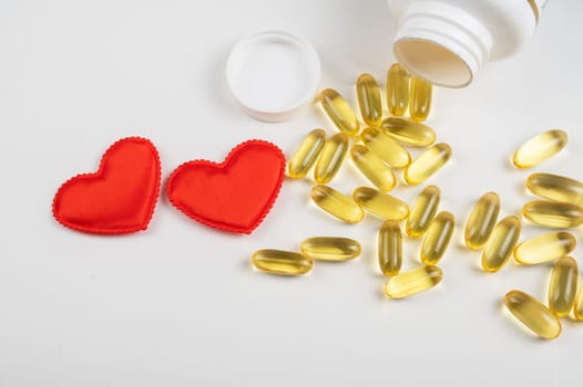 Gold fish oil isolated on white background with red hearts. Pile of fish oil with Omega 3 acid. Concept of healthy heart