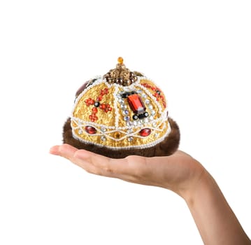 Woman's hand holding a gold crown over white background. Medieval period concept.