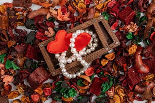 Pearl jewelry with red hearts in wooden box on dry flowers background. Valentines day gift concept