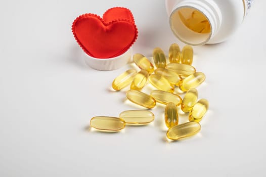 Gold fish oil isolated on white background with red hearts. Pile of fish oil with Omega 3 acid. Concept of healthy heart