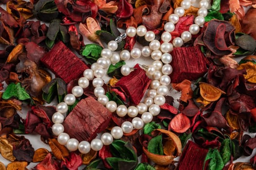 Pearl jewelry on dry flowers background.