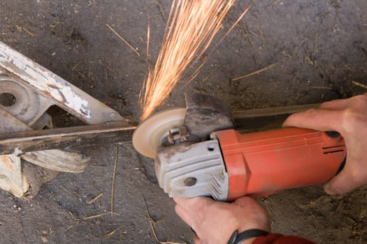 The worker cutting metal with grinding machine