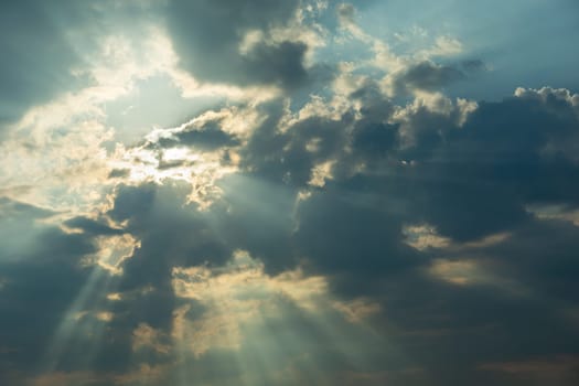 The sun behind the clouds and the sun's rays, summer day