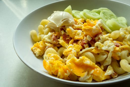 Scrambled eggs with bacon and mayonnaise in a white plate
