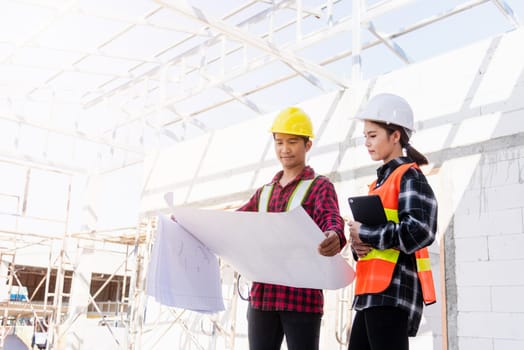 Architect and client discussing the plan with blueprint of the building at construction site. Asian engineer foreman worker man and woman working talking on drawing paper to checking project