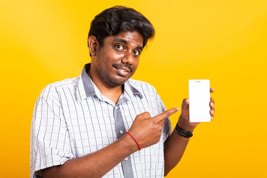 Asian happy portrait young black man smile standing wear shirt making finger pointing on smart digital mobile phone blank screen isolated, studio shot yellow background with copy space