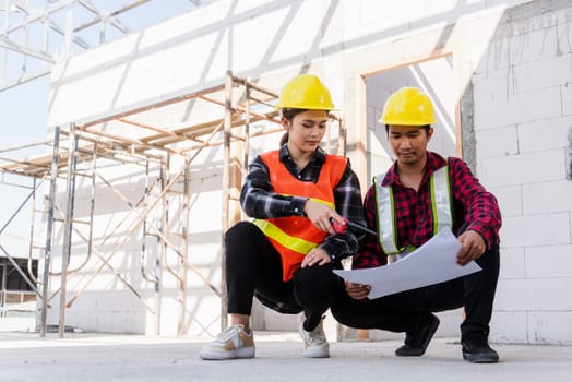 Architect and client discussing help create plan with blueprint of the building at construction site. Asian engineer foreman worker man and woman meeting talking on drawing paper project, team work