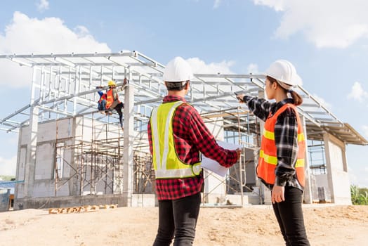 Back two architect and client discussing help create plan with blueprint home building at construction site. Asian engineer foreman worker man and woman meeting talking on drawing paper project