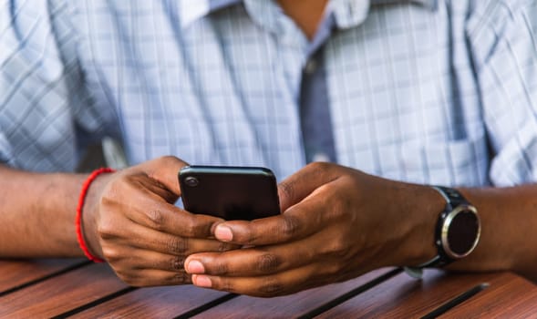Happy Asian black businessman person holding a modern digital smart phone blank screen device technology and connecting networking online at the coffee cafe shop