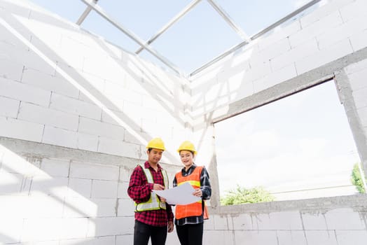 Architect and client discussing the plan with blueprint of the building at construction site. Asian engineer foreman worker man and woman working talking and checking on draw paper to checking project
