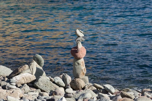 Stone pyramid on the beach in the sand in front of the sea