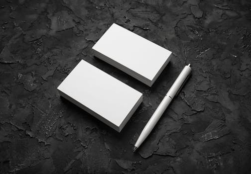 Blank business cards and pen on black stone background. Mockup for branding identity. Template for graphic designers portfolios.