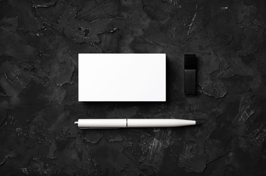 Photo of blank business cards, pen and usb flash drive on black stone background. Template for ID. Flat lay.