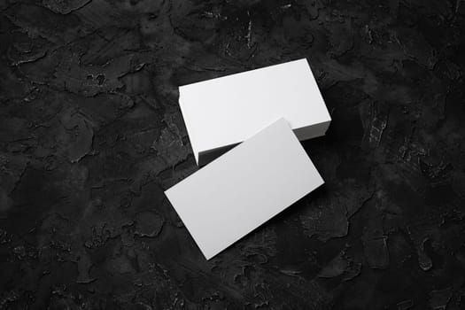 Photo of blank business cards on black stone background. Template for ID.