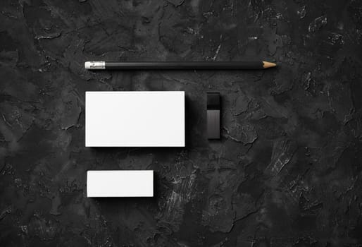 Photo of business cards, pencil, eraser and usb flash drive on black stone background. Branding mock up. Flat lay.