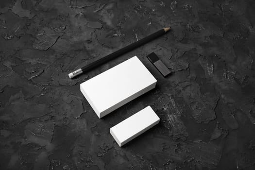 Blank business cards, pencil, eraser and usb flash drive on black stone background. Blank stationery set.