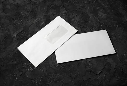 Two blank envelopes on black stone background. Back and front. Template for branding identity.