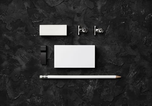 Blank stationery set. Blank business cards, pencil, eraser, usb flash drive and clips on black stone background. Flat lay.