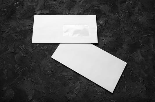 Blank paper envelopes on black stone background. Front and back side. Template for branding identity.
