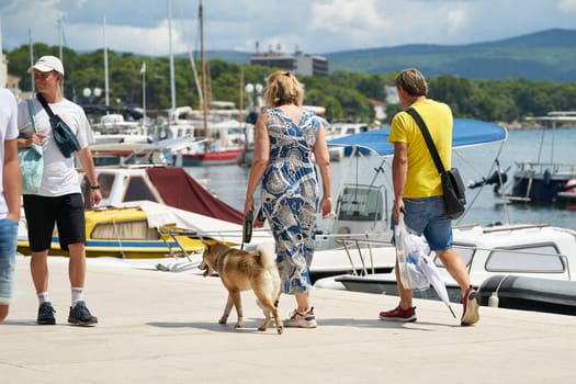 Couple with dog on the promenade in the port of the town of Krk on the Adriatic Sea in Croatia
