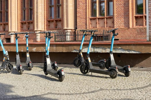 parked e-scooters of the company OKAI in front of the town hall of the city of Kolobrzeg in Poland are ready to be borrowed
