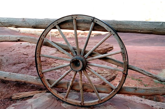 Old iron and wood wagon wheel against and old wooden fence