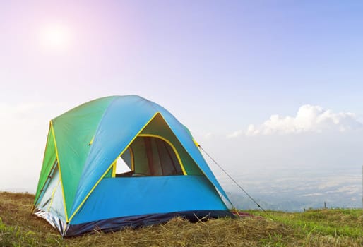 Tent on a grass under in morning sunrise and blue sky