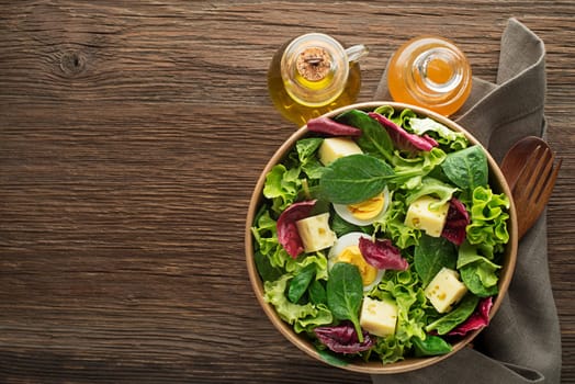 Healthy Green salads with fresh egg and cheese on wooden background close up