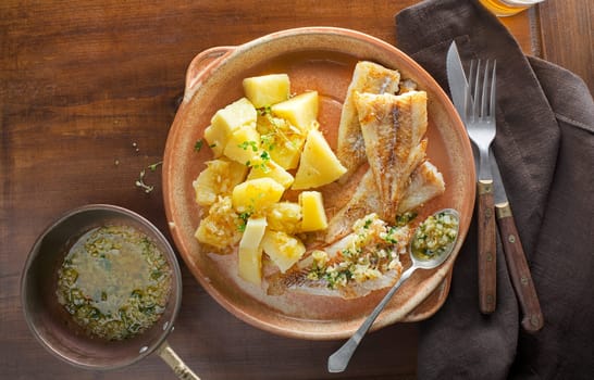 Fish dish - fried cod fillet with boiled potatoes on wooden table.  Mediterranean food with fillet fish
