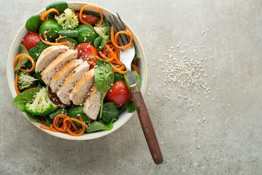 Healthy green salad with chicken breast and cooked vegetables on grey background. Healthy meal