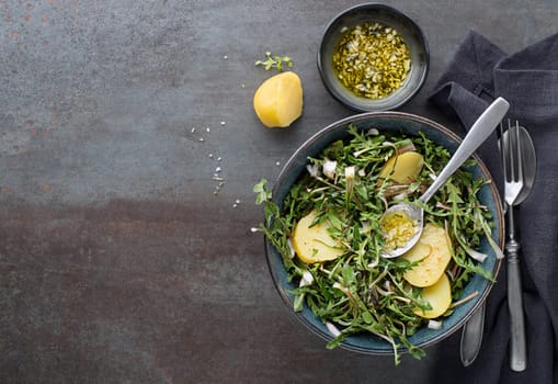 Healthy dandelion salad with potatoes and dressing on grey background close up