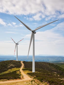 Wind turbines on a beautiful blue sky with clouds in a mountain wind farm in Sardinia. Renewable energy concept, green energy generation. Energy industry.