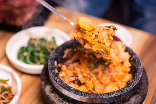 Bibimbap in a black heated stone bowl, Korean traditional dish- bibimbap mixed rice with vegetables Include beef and fried egg, Japanese hot pot food