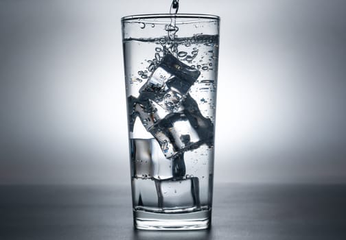 The image of pouring drinking water, into a glass with ice, that makes one feel refreshed on blurred shadow background