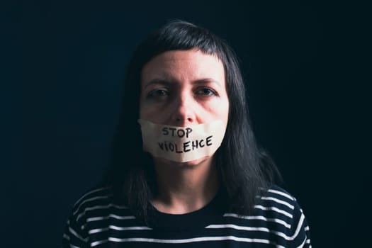Women violence and abused concept. Stop domestic violence against women and human trafficking.Woman with tape on mouth and stop violence text