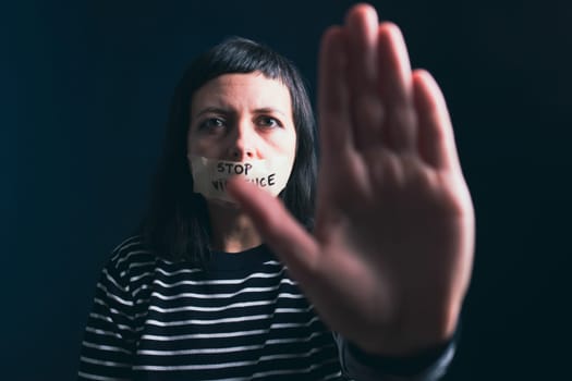 Women violence and abused concept. Stop domestic violence against women and human trafficking.Woman with tape on mouth and stop violence text