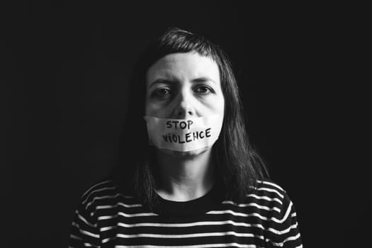 Women violence and abused concept. Stop domestic violence against women and human trafficking.Woman with tape on mouth and stop violence text