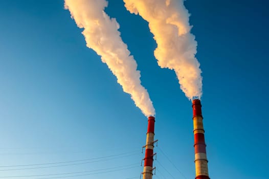 white smoke is coming out of the pipes in the blue sky. High quality photo