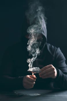 Addict/junkie man preparing drugs. The concept of crime and drug addiction.