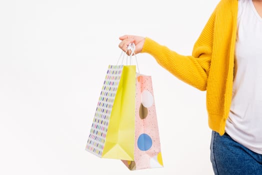 Happy young female hold many packets within arms, woman hand she wears a yellow shirt holding shopping bags multicolor isolated on white background, Black Friday sale concept