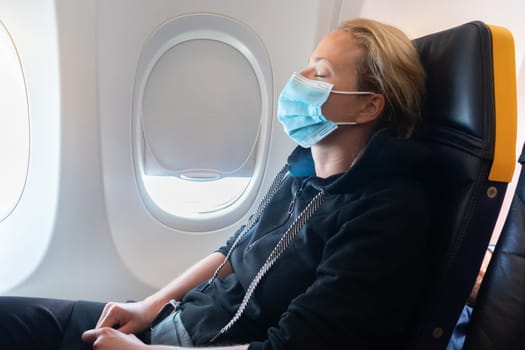 A young woman wearing face mask is traveling on airplane , New normal travel after covid-19 pandemic concept