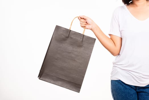 Closeup female holds in hand with black clear empty blank craft paper gift bag, women hand holding black shopping bag isolated on white background, shopping day concept