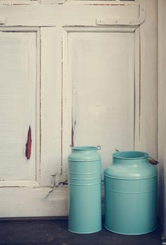 Vintage blue milk canisters in front of rustic door.