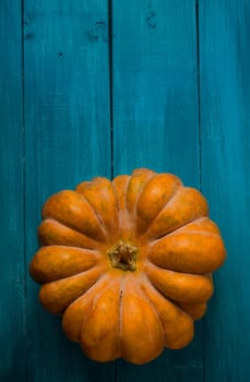 Orange pumpkin on blue rustic wooden table.