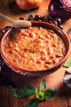Spicy baked beans in traditional clay bowl