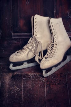 White ice skates on rustic wooden background
