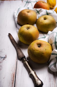 Yellow apples on white rustic table with old knife