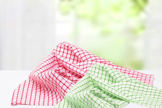 Empty desk table with red and green checkered tablecloth over abstract bright light green yellow spring or summer background. Template for your food and product display montage.