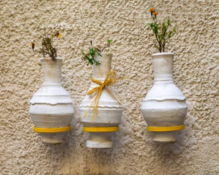 Three adjacent handmade white pottery vases, arabic: Kolla, hanged on rough stone white wall